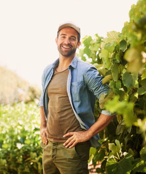Portrait of a cheerful young farmer posing in the fields on his farm.